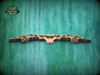 A wooden carving or sculpture is displayed against a textured green background.