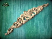 Load image into Gallery viewer, A decorative wooden carving with intricate floral and scrollwork designs is displayed against a teal background.
