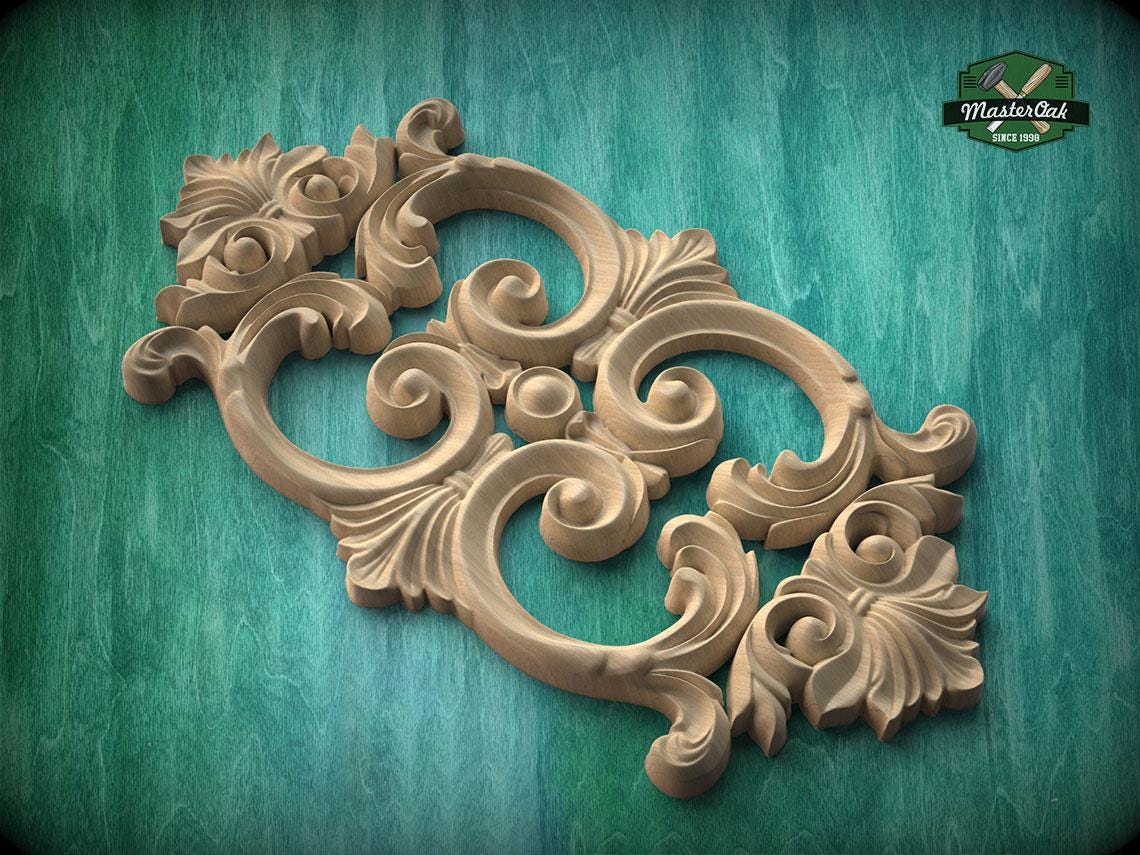 a decorative wooden carving with intricate scrollwork and floral elements, set against a green background.
