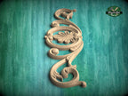 A decorative wooden carving with an intricate floral design is displayed against a teal-colored background.
