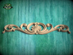 A decorative wooden carving with a floral design is displayed against a teal-colored background.