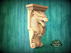 A carved wooden dragon head with a crest and wings, displayed against a green background.