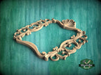 A wooden ornate frame with intricate scrollwork and a shell-like design, set against a green textured background.