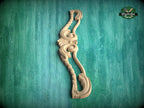 A wooden carving of a decorative piece is displayed against a green textured background.
