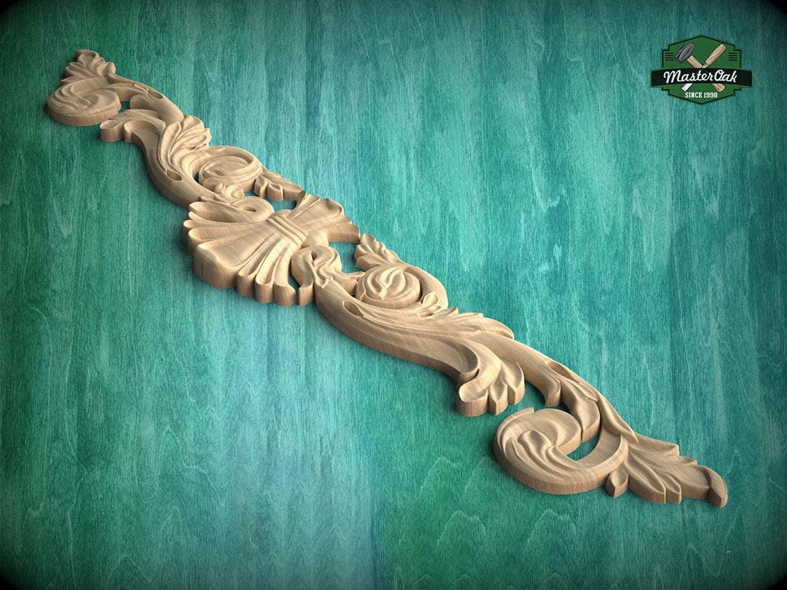 A decorative wooden carving with intricate floral and scrollwork designs is displayed against a green background.