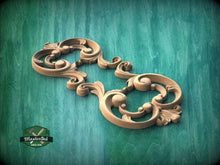 Load image into Gallery viewer, A decorative wooden carving with intricate scrollwork and floral elements is displayed against a green background.
