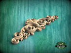 A decorative wooden carving with intricate scrollwork is displayed against a green background.