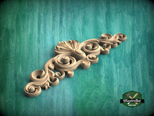 Load image into Gallery viewer, A decorative wooden carving with intricate scrollwork is displayed against a green background.
