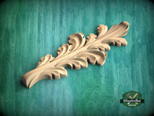 Load image into Gallery viewer, A wooden carving of a leaf-like design is displayed against a green background.
