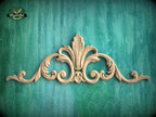 A decorative wooden carving with an ornate, floral-inspired design is displayed against a teal-colored background.