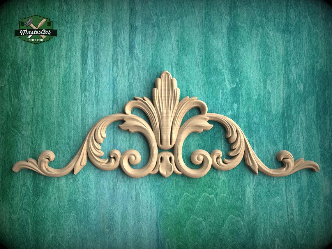 A decorative wooden carving with an ornate, floral-inspired design is displayed against a teal-colored background.