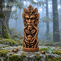 A wooden sculpture of a face with leaves and an acorn, placed on a mossy rock in a forest setting.