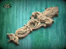 Load image into Gallery viewer, A wooden carving with intricate floral and scroll designs is displayed against a green background.
