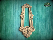 Load image into Gallery viewer, an ornate, carved wooden frame with intricate floral and scrollwork designs, mounted on a green textured wall.
