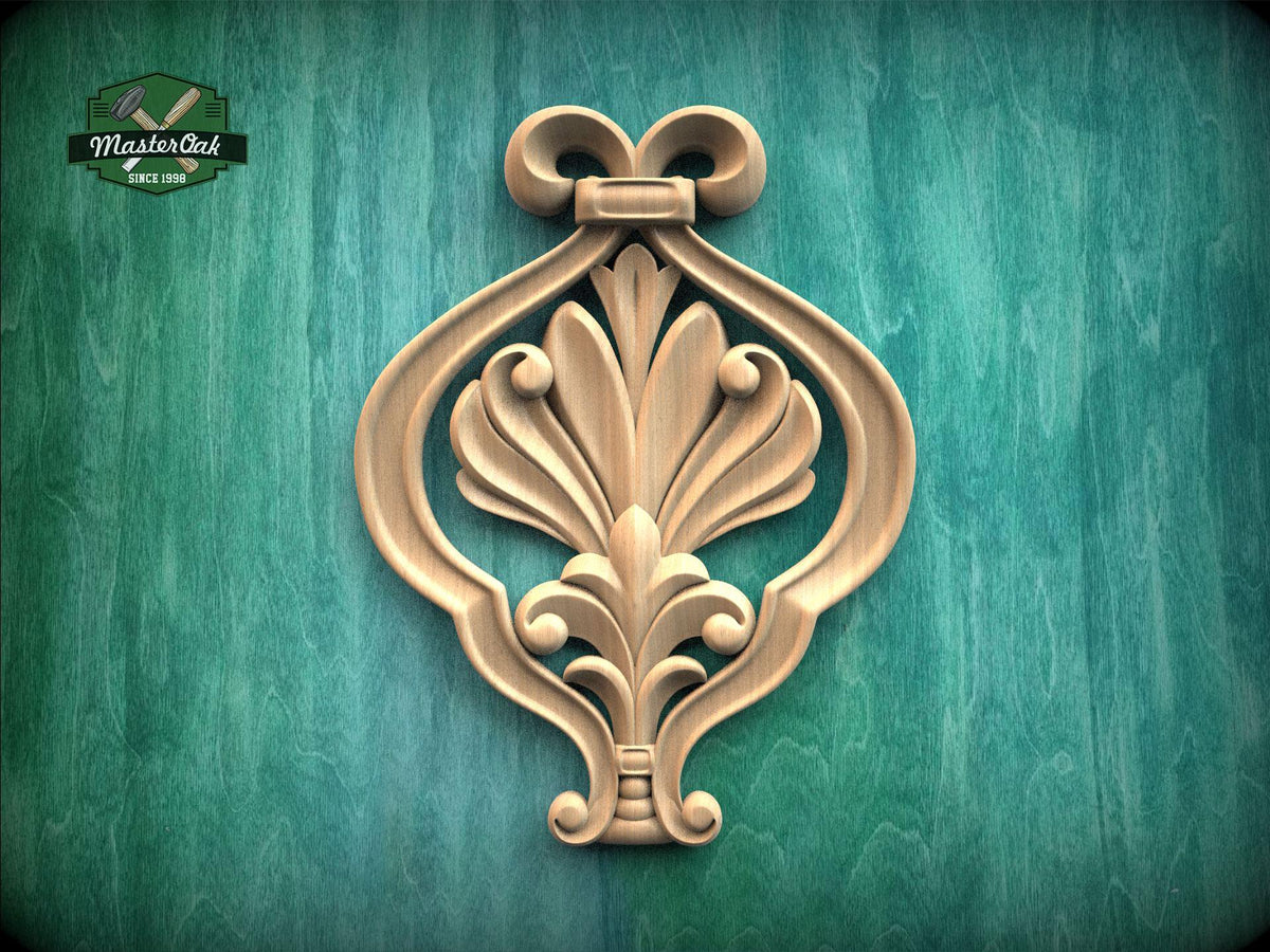 a decorative wooden ornament with an intricate floral design, mounted on a green wooden surface.