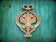Load image into Gallery viewer, a decorative wooden ornament with an intricate floral design, mounted on a green wooden surface.
