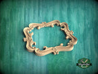 A wooden ornate frame with intricate scrollwork is displayed against a green textured background.