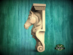 A carved wooden horse head mounted on a wall, with a green background.
