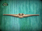 A decorative wooden object with a curved, ornate design is displayed against a green textured background.