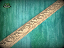 Load image into Gallery viewer, A decorative wooden border with intricate floral designs is displayed against a green wooden background.
