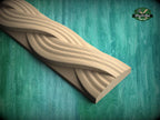 A wooden carving with a curved, wavy design is displayed against a green background.