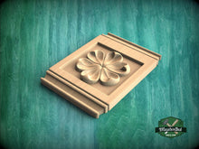 Load image into Gallery viewer, A wooden panel with a carved flower design is displayed against a green background.
