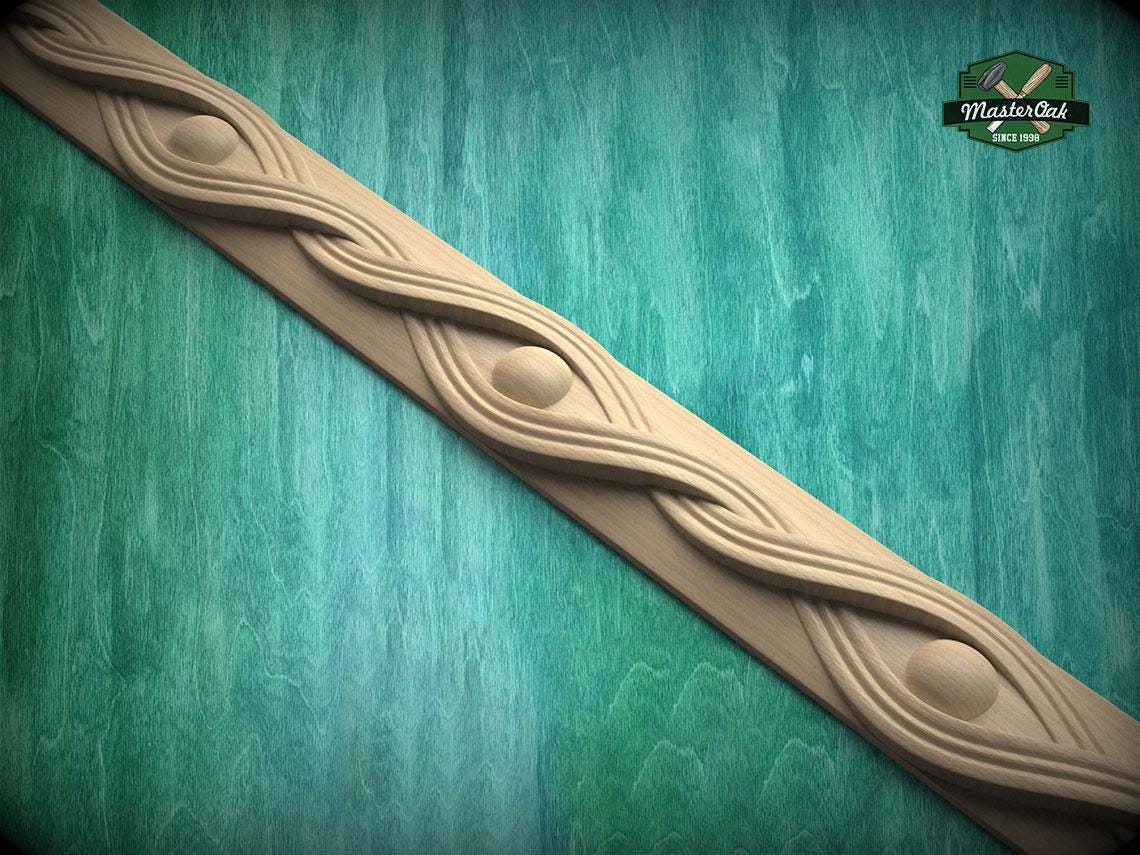 A decorative wooden molding with a swirling, eye-like design is displayed against a green textured background.