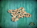 A decorative wooden carving with intricate floral patterns is displayed against a green textured background.