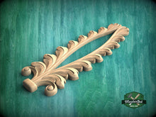 Load image into Gallery viewer, A decorative wooden carving with a leaf-like design is displayed against a green background.
