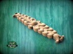 A wooden carving of a flower-like design is displayed against a green background.
