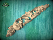 Load image into Gallery viewer, A decorative wooden carving with intricate floral and scroll designs is displayed against a teal background.

