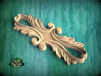 A decorative wooden carving with an intricate, flowing design is displayed against a green background.