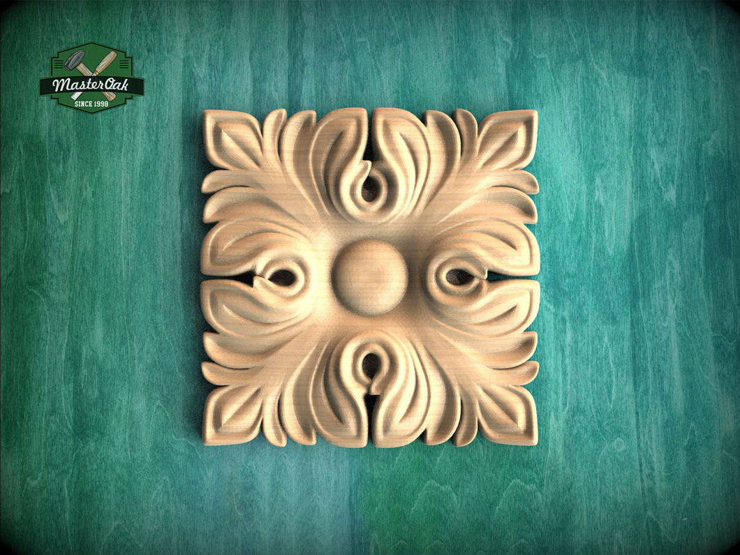 a square, ornate, carved wooden piece with a floral design, placed on a green wooden surface.