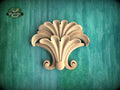 a decorative wooden piece with a floral design, set against a green background.