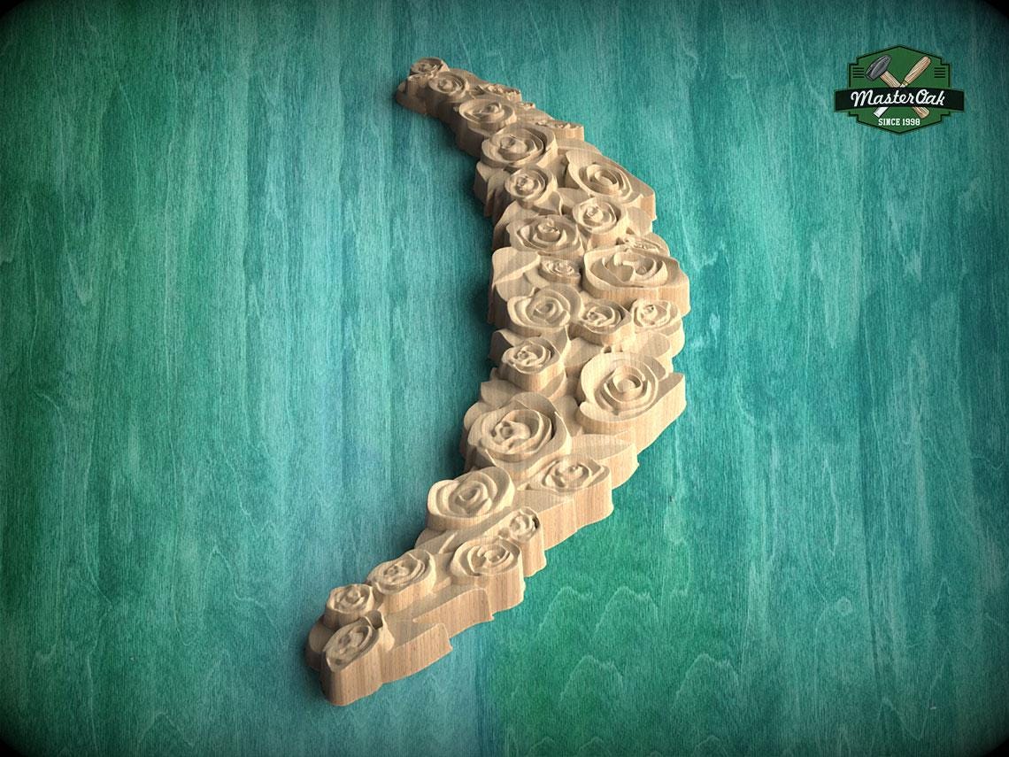 A wooden carving of a crescent moon shape, with intricate rose-like patterns carved into it, set against a green background.