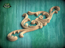 Load image into Gallery viewer, A decorative wooden carving with intricate scrollwork is displayed against a teal background.
