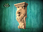 A carved wooden wolf head on a wall, with a decorative scroll design around it, against a green background.