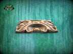 A wooden carving or sculpture is displayed against a green background.