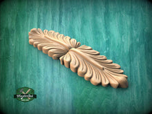 Load image into Gallery viewer, A wooden carving of a leaf-like design is displayed against a green background.
