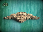 A decorative wooden carving with intricate floral and scrollwork designs is displayed against a green textured background.